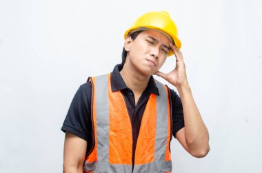 Yorgun görünen Asyalı inşaat işçisi çok çalıştıktan sonra yorgun ve baş ağrısı çekiyor. Sarı güvenlikli adam sıkı şapka ve turuncu yelek fazla çalıştı..