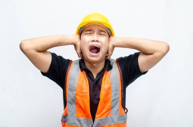 Asyalı Erkek İnşaat İşçisi 'nin Orange Vest ve Sarı Kasklı Kızgın, Kızgın, Üzgün, Kızgın İfadesiyle Aşırı Çalışmış Konsepti. 