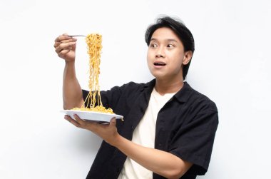 Siyah gömlekli genç bir Asyalı ve beyaz tişörtlü bir tabak kızarmış erişteli beyaz arka planda izole edilmiş. 