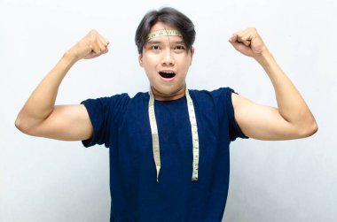 Genç, zinde, sağlıklı Asyalı Mutlu Vücut Ölçümü Bantları. Başarılı Mutlu Diyet Konsepti. Mavi gömlekli genç Asyalı atletik görünüyor.