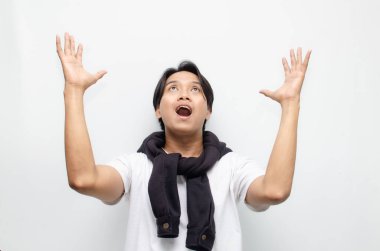 Neşeli bir zaferi kutlamak için sıradan kıyafetler içindeki heyecanlı ve şaşırmış Asyalı genç adam. Başarı, mutluluk ve başarı kavramları için mükemmel.