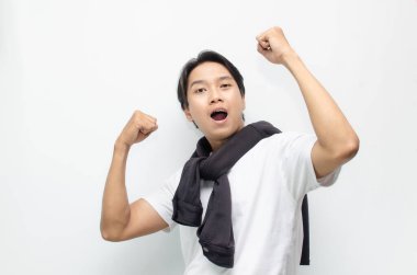 Neşeli bir zaferi kutlamak için sıradan kıyafetler içindeki heyecanlı ve şaşırmış Asyalı genç adam. Başarı, mutluluk ve başarı kavramları için mükemmel.