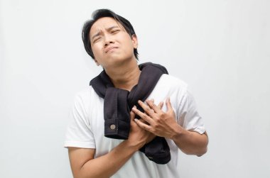 Şiddetli acılar içinde göğsünü sımsıkı tutan genç bir Asyalı. Şiddetli rahatsızlık ve olası sağlık sorunlarını tasvir ediyor. Sağlık ve tıbbi farkındalık kavramları için mükemmel.