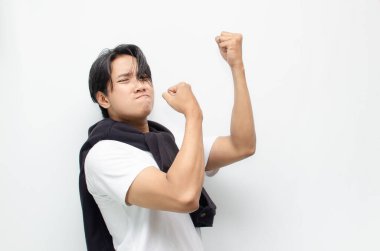 Neşeli bir zaferi kutlamak için sıradan kıyafetler içindeki heyecanlı ve şaşırmış Asyalı genç adam. Başarı, mutluluk ve başarı kavramları için mükemmel.