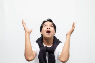 Neşeli bir zaferi kutlamak için sıradan kıyafetler içindeki heyecanlı ve şaşırmış Asyalı genç adam. Başarı, mutluluk ve başarı kavramları için mükemmel.