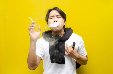 Young Asian man holding his chest in pain while smoking or vaping, with smoke rising. Depicts the health risks of smoking, including chest pain, respiratory issues, and long-term damage clipart