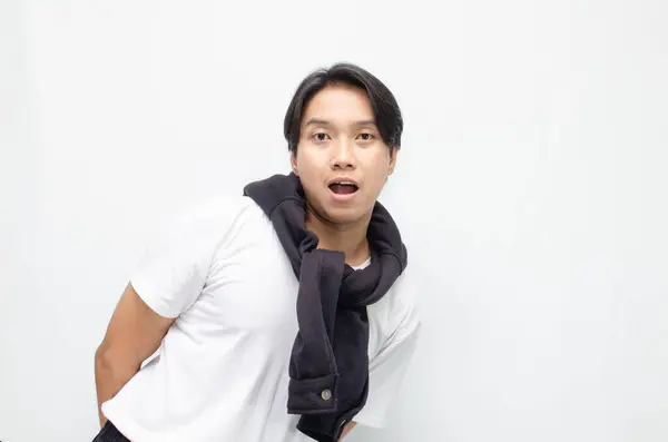 Neşeli bir zaferi kutlamak için sıradan kıyafetler içindeki heyecanlı ve şaşırmış Asyalı genç adam. Başarı, mutluluk ve başarı kavramları için mükemmel.