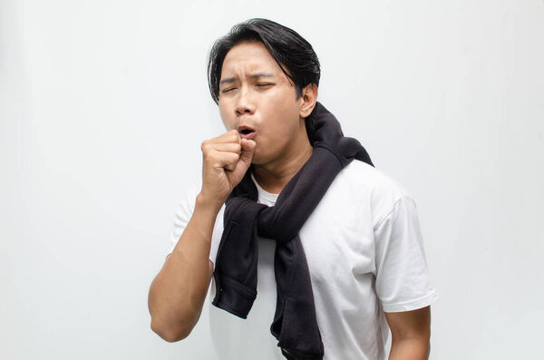 Young Asian man coughing and showing flu symptoms with a feverish look. Ideal for healthcare, illness, and seasonal flu awareness concepts