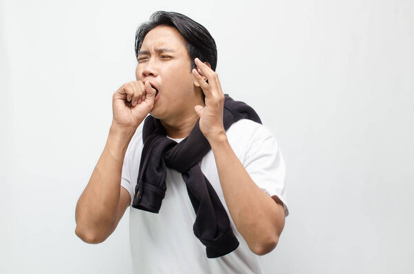 Young Asian man coughing and showing flu symptoms with a feverish look. Ideal for healthcare, illness, and seasonal flu awareness concepts