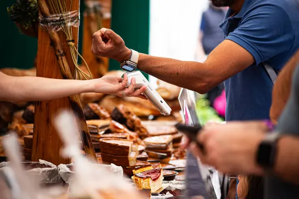 Bir kişi, pastanede akıllı bir kasayla günlük mali işlemlerde giyilebilir teknolojinin kolaylığını ve modern kolaylığını sergileyerek ulaşılamaz bir ödeme yapar..