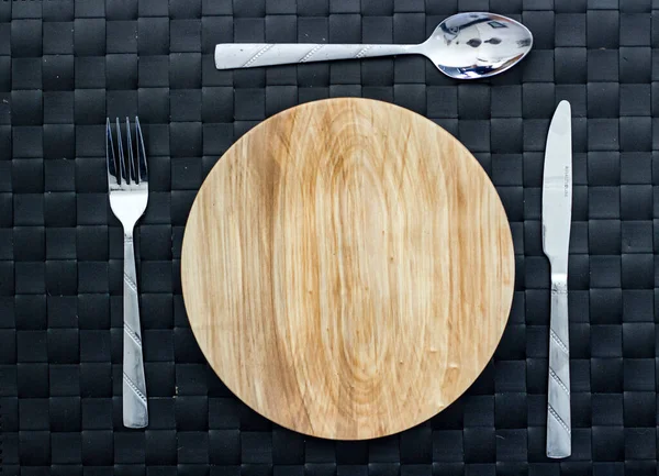 Bıçak, çatal ve siyah arkaplan ile el yapımı temiz ahşap tabak. Üst görünümü ayarla.