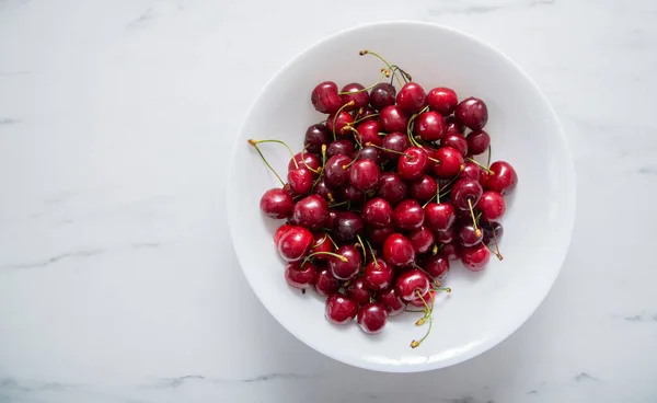 stock image Juicy cherries fruit in a white plate on a white surface. background