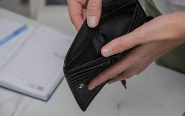 Elinde boş siyah deri cüzdan tutan genç bir kadın var. Nakitsiz stres, iflas konsepti.