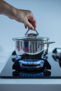 Metal tencere alevlerle gaz sobasının üstünde duruyor.