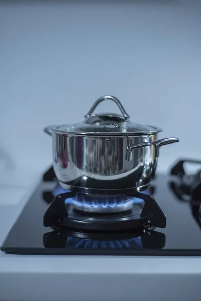 Metal tencere alevlerle gaz sobasının üstünde duruyor.