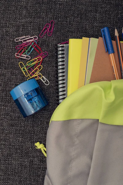 Okul malzemeleriyle dolu bir okul çantası siyah yüzey üzerine okula dönüş konsepti.