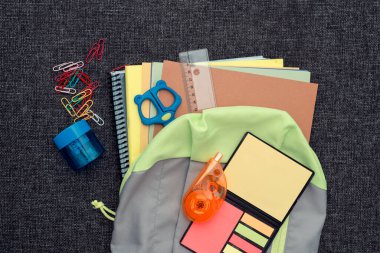 Okul malzemeleriyle dolu bir okul çantası siyah yüzey üzerine okula dönüş konsepti.