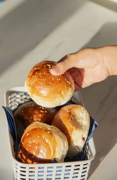 Human hand holding fresh burger bread.lot of burger in a basket
