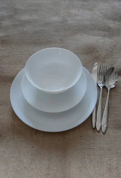 An empty white plates on the brown surface, overhead flat lay