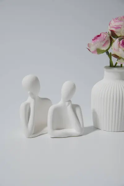 Küçük beyaz seramik vazo, insan çiftinin heykeli. Beyaz arkaplanda el yapımı sembolik seramik figürler