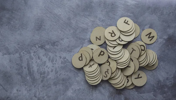 Kare ahşap kiremitlerden yapılmış Türk alfabesi mavi arkaplana saçılmış.