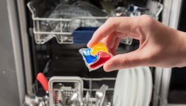 Kadın bulaşık makinesine deterjan koyuyor. Ev idaresi, ev işleri, ev işleri.