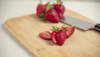 Çilekler dilimlenmiş. Tahtanın üzerinde ve bıçağın yanında yatıyorlar. sağlıklı yiyecekler