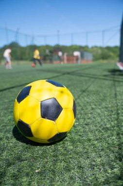 Futbol sahasında sarı bir futbol topuna yaklaş.