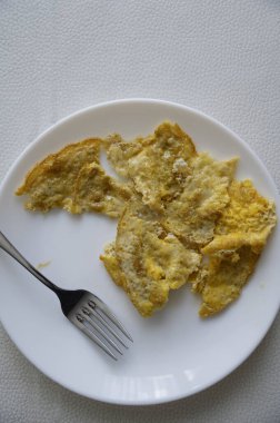 Beyaz tabak ve çatalda yumurta omleti.