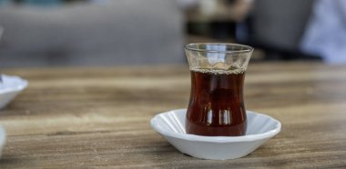 Masanın üzerinde klasik bir bardak ve çay tabağı içinde bir bardak Türk çayı.