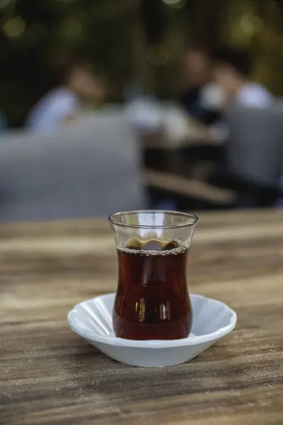 Masanın üzerinde klasik bir bardak ve çay tabağı içinde bir bardak Türk çayı.