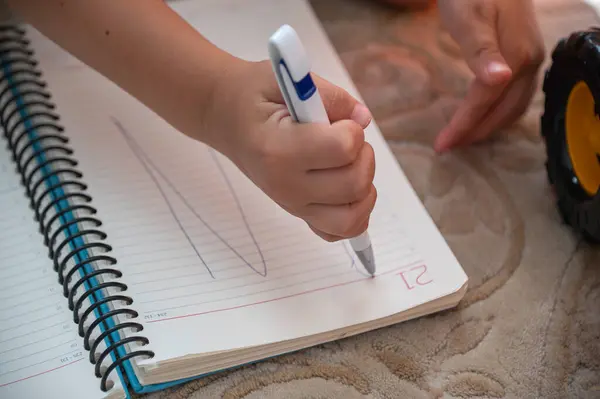 Çocuk yazmayı öğreniyor. Kalemi eline aldı ve bir deftere yazdı. Otizm kavramı. Kalemle çocuğun eli.