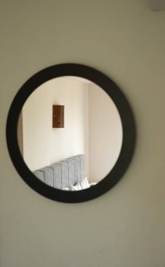 Otel odasının duvarında yuvarlak bir ayna.