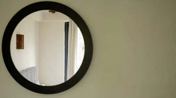 Otel odasının duvarında yuvarlak bir ayna.