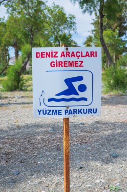 Yüzücüler için uyarı işareti Türkçe plajda duruyor