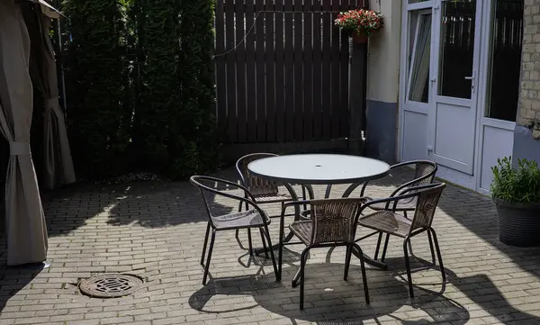 Güneşli bir günde dışarıda boş metal sandalyeler ve oval masa.