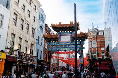 Londons Çin Mahallesi 'nde, geleneksel Çin fenerleriyle süslenmiş karmaşık ve renkli Çin Mahallesi Kapısı' nın olduğu canlı bir sahne. Bu hareketli bölge, Asya mutfağının, dükkanlarının ve kutlamalarının eşsiz bir karışımını sunan kültürel çeşitliliğin merkezidir.