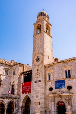 Dubrovniks 'in tarihi şehrinde çarpıcı bir saat kulesi var. Zarif mimari ve detaylı tasarım, UNESCO Dünya Mirası 'nın cazibesini sergileyen, etrafındaki taş binalar ve canlı mavi gökyüzü tarafından tamamlanıyor.