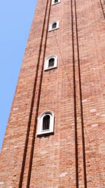 Venedik, İtalya 'daki St. Marks Bazilikası' nın ikonik Campanile 'inin alçak açılı görüntüsü. Bu tuğla çan kulesi, zamansız mimari zarafetini ve tarihsel önemini gözler önüne seren parlak mavi gökyüzüne karşı dimdik ayakta duruyor..