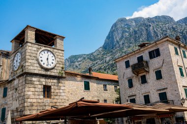 Karadağ 'ın Kotor kentinin tarihi simgelerinden biri olan St. Tryphon' un çarpıcı katedrali, ikiz çan kuleleriyle yemyeşil dağlardan oluşan bir zemin üzerinde görkemli bir şekilde duruyor. Aşağıdaki hareketli kare bu tarihi ve ruhani yere canlılık katıyor.