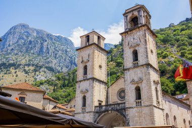 Karadağ 'ın Kotor kentinin tarihi simgelerinden biri olan St. Tryphon' un çarpıcı katedrali, ikiz çan kuleleriyle yemyeşil dağlardan oluşan bir zemin üzerinde görkemli bir şekilde duruyor. Aşağıdaki hareketli kare bu tarihi ve ruhani yere canlılık katıyor.