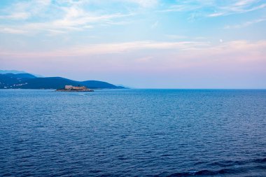 Günbatımında Adriyatik Denizi 'nde gökyüzü mavi ve pembeye boyanmış ıssız bir ada manzarası. Sakin sular ve doğal manzara rahatlatıcı ve canlandırıcı bir atmosfer yaratır.