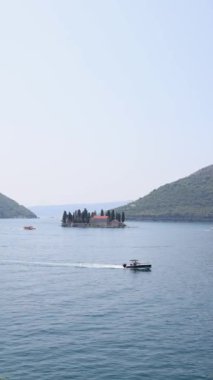 Karadağ 'ın Kotor Körfezi' ndeki iki ikonik adanın çarpıcı manzarası: Kayaların Leydisi ve Aziz George. Sakin mavi sular ve yemyeşil dağlarla çevrili bu resim Adriyatik kıyılarının dingin güzelliğini ve kültürel zenginliğini yansıtıyor.