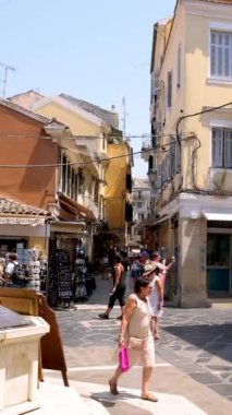 Yunanistan 'ın Korfu Kasabası' nın göbeğinde turist ve yerlilerle dolu canlı bir cadde. Tarihi mimari, dükkanlar ve kültürel öğelerin karışımı bu Akdeniz adasının özünü yansıtan canlı bir atmosfer yaratır.