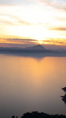 Basilicata, Maratea 'dan Tyrhenian Denizi üzerinde nefes kesici gün batımı manzarası. Sudaki altın yansımalar, dağlık kıyı şeridi ve huzurlu gökyüzü bu manzarayı İsa 'nın yakınındaki yüksek bir noktadan mükemmel bir görüntü haline getiriyor.