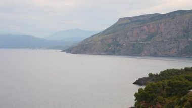 İtalya 'nın Basilicata bölgesindeki Maratea yakınlarındaki sahil şeridinin panoramik manzarası. Sahne dramatik bir uçurum, yoğun bir çam ormanı ve sakin bir Tyrhenian Denizi yakalıyor.