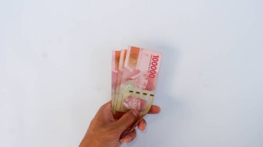 Bir kaç Endonezya Rp 'si. 100.000, insan eli beyaz bir paspasın üzerinde. Endonezya 'nın para birimi Rupiah' tır