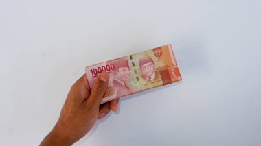 Bir kaç Endonezya Rp 'si. 100.000, insan eli beyaz bir paspasın üzerinde. Endonezya 'nın para birimi Rupiah' tır
