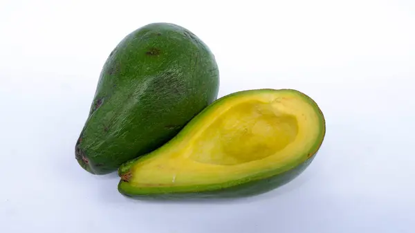 Bölünmüş ve olgunlaşmış yeşil avokado meyvesi. İnsan sağlığı için birçok vitamin içeriyor. Beyaz bir paspasın üzerine yerleştirilmiş.