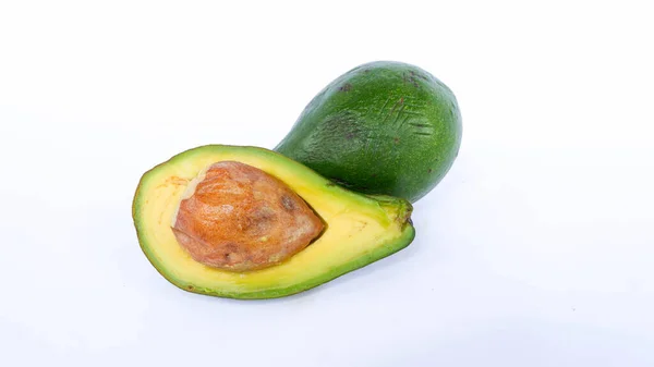 Bölünmüş ve olgunlaşmış yeşil avokado meyvesi. İnsan sağlığı için birçok vitamin içeriyor. Beyaz bir paspasın üzerine yerleştirilmiş.